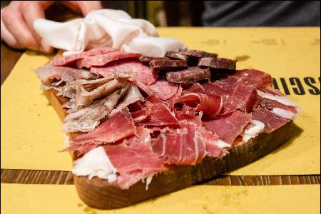 An assortment of sliced cured meats served on a wooden board.