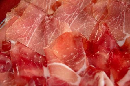 Thinly sliced cured ham arranged on a plate.