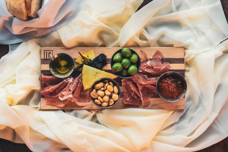 Explore charcuterie board images & ideas featuring a gourmet selection with an assortment of cured meat, nuts, olives, dips, and dried seaweed, all elegantly presented on a wooden platter